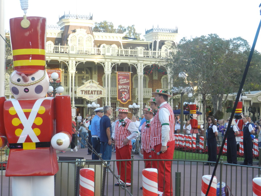 Christmas at Walt Disney World with red and white toy soldiers and Dapper Dans singing on Main Street U.S.A. Keep reading to learn about the best Disney Resorts at Christmas!