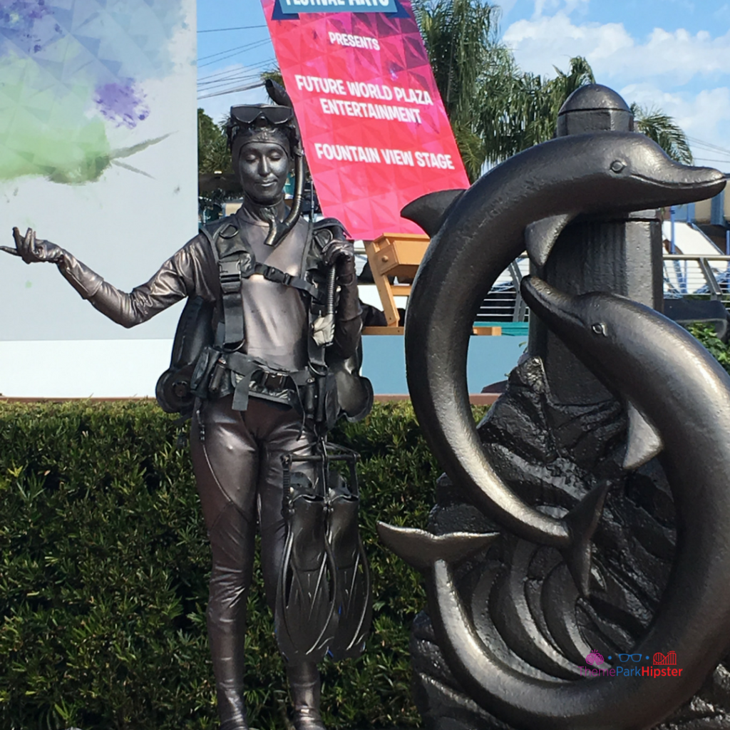 2024 Epcot Festival of the Arts Live Art Sculpture with Woman Standing Next to Gray Dolphin. Keep reading to learn about the Epcot Festival of the Arts seminars!