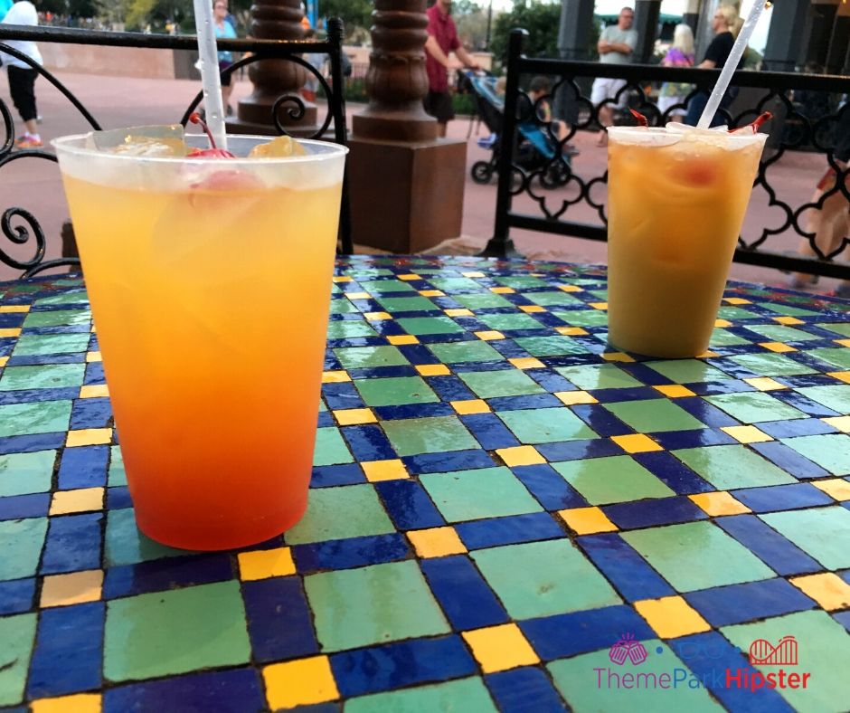 Spice Road Table at Epcot Mediterranean Journey Orange Cocktail on colorful table. Keep reading for the best Epcot drinking around the world passport ideas!