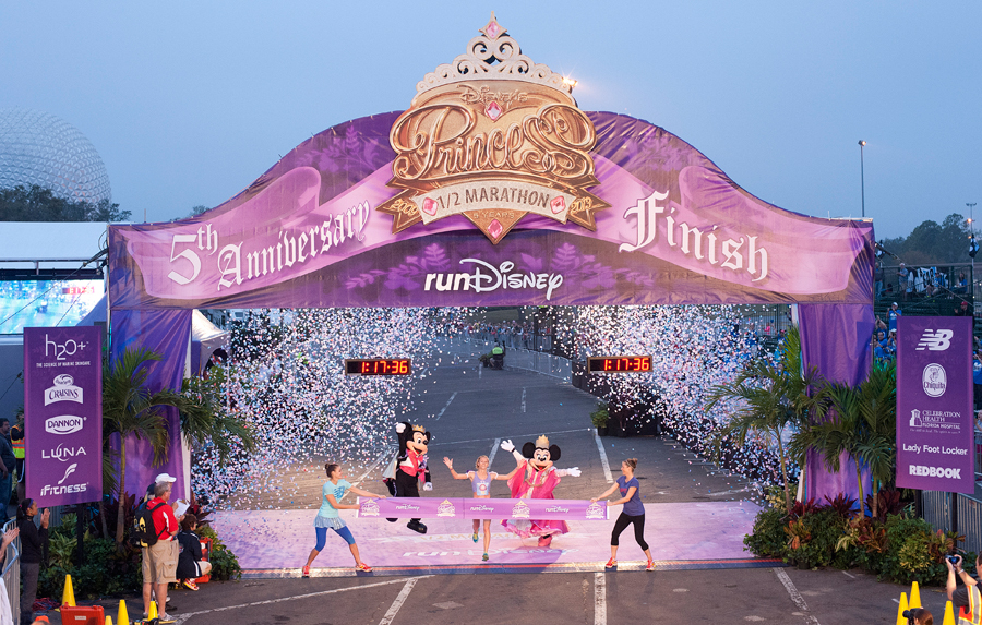 RunDisney Princess Marathon Weekend with Mickey and Minnie Mouse at the finish line with confetti all through the air. Keep reading to find out all you need to know about how to become a runDisney volunteer.