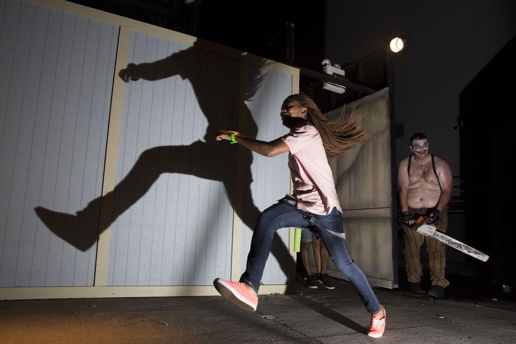 Halloween Horror Nights Tips young lady running from scareactor. Giggles and Gore 2014. Keep reading to know what to bring to Halloween Horror Nights in your HHN packing list.