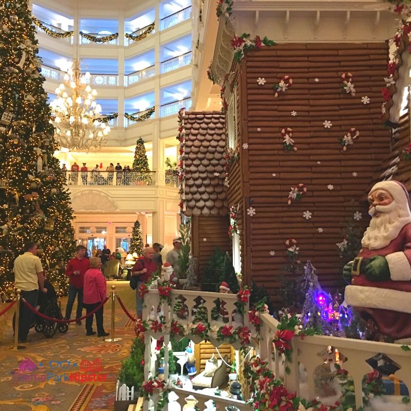  Affichage de la Maison en Pain d'Épice Disney Grand Floridien avec le Père Noël sur le porche et l'arbre de Noël en arrière-plan