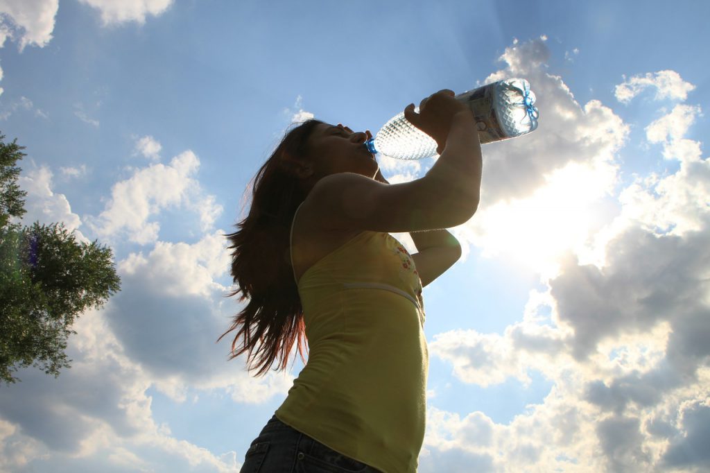 Tips for  theme park heat in Florida with lady drinking water in the summer.