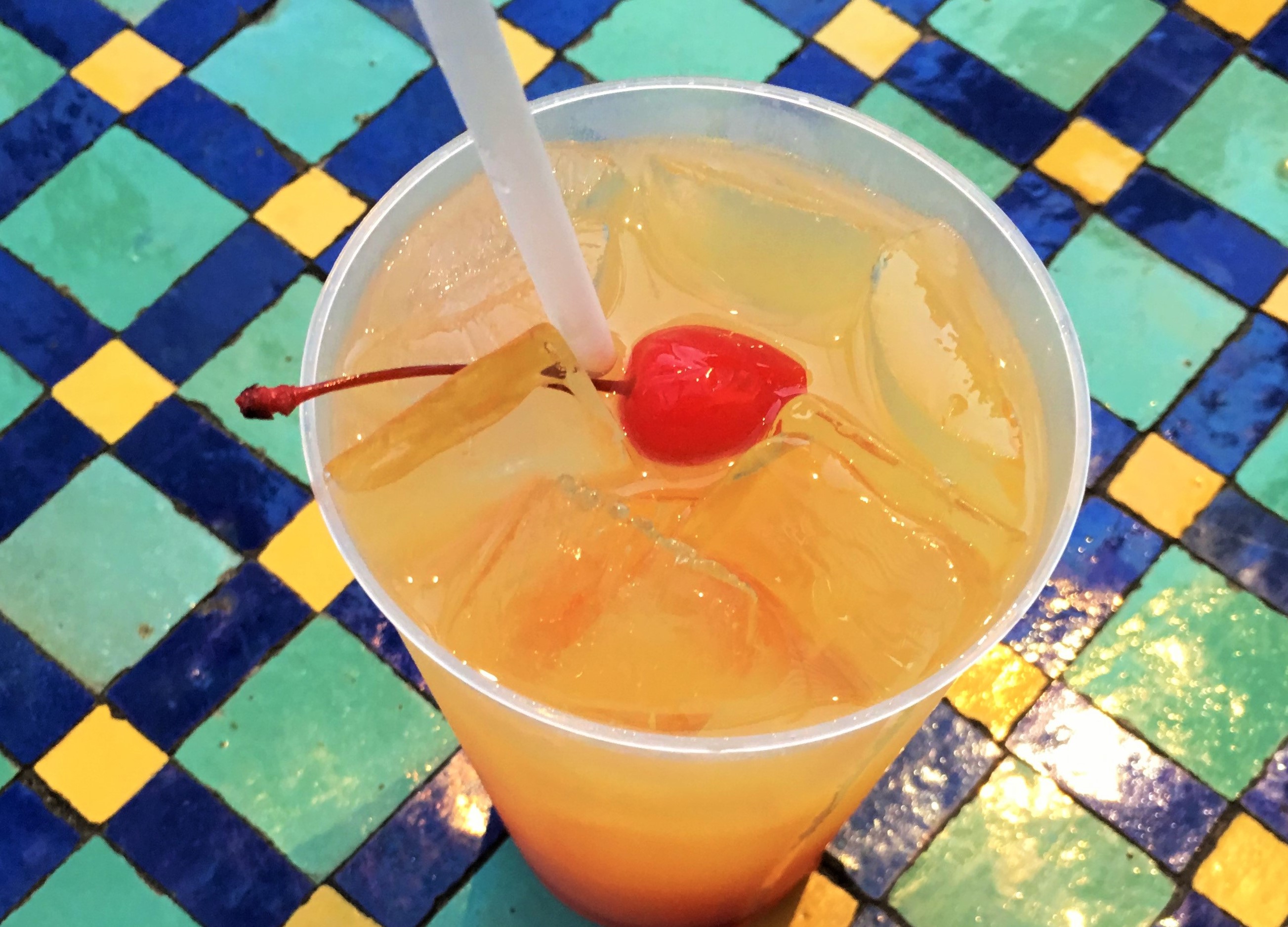 Mediterranean Journey tropical drink at Epcot in Morocco Pavilion sitting on mosaic table. Keep reading to get the Do’s and Don’ts of Drinking Around the World at Epcot Tips.