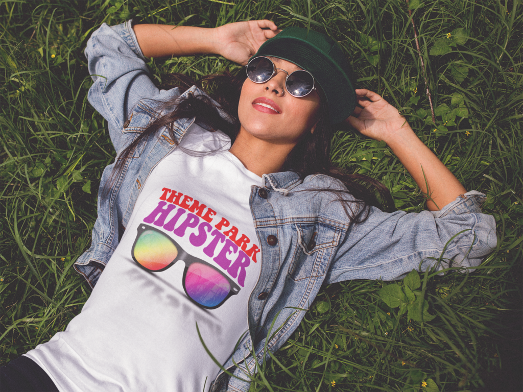 Theme park fan laying in the grass resting in a ThemeParkHipster Logo T-Shirt, sunglasses and cap. Keep reading if you want to find out more about what to wear to Universal Studios Florida.