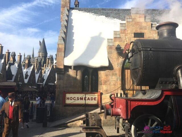 Hogsmeade at Universal with steam coming from engine and guests walking around. One of the best Wizarding World of Harry Potter photo spots.