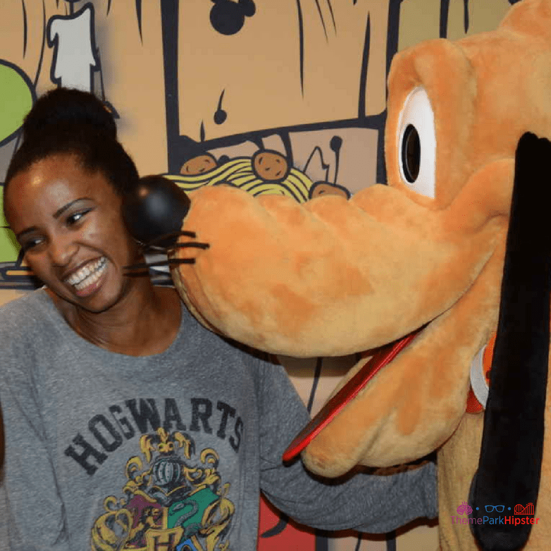 NikkyJ of ThemeParkHipster smiling with Pluto Dog. Free photos at a chase card member is one of the little Disney World tips to remember.