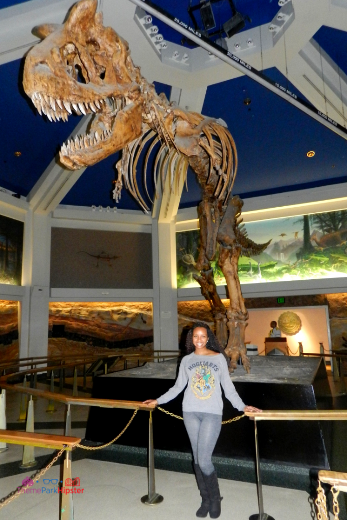 NikkyJ of ThemeParkHipster in front of large Dinosaur at Animal Kingdom.