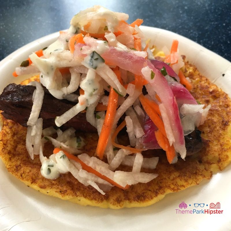 Charred Chimichurri Skirt Steak on a smoked corn cake with pickled vegetable slaw and cilantro aioli at Flavors from Fire Epcot