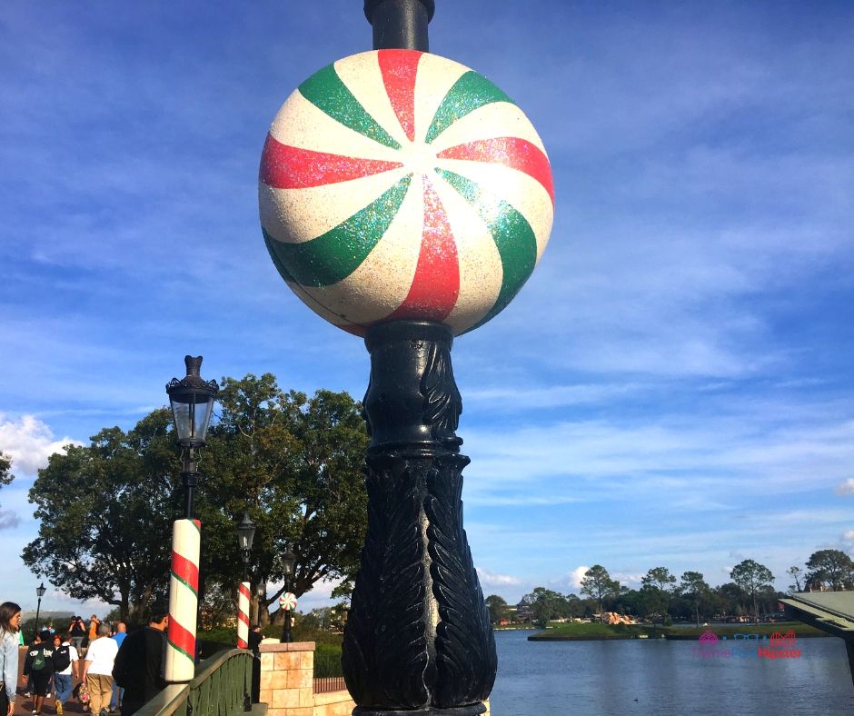 Epcot Festival of the Holidays 3 France Pavilion with Green Red and White Peppermint Light Pole for the Epcot Candlelight Processional. Keep reading to learn more about the Epcot Candlelight Processional and Christmas at Disney World.