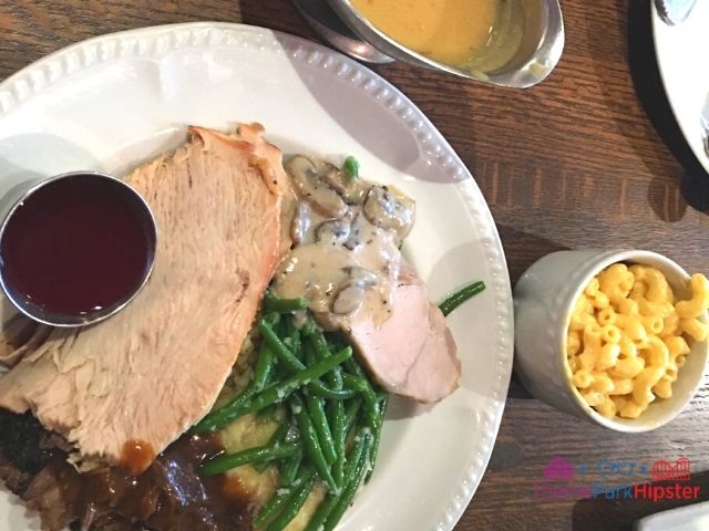 Liberty Tree Tavern Magic Kingdom Turkey Mashed Potatoes Gravy Mac and Cheese on white plate. Keep reading to learn how to do Thanksgiving Day at Disney World.