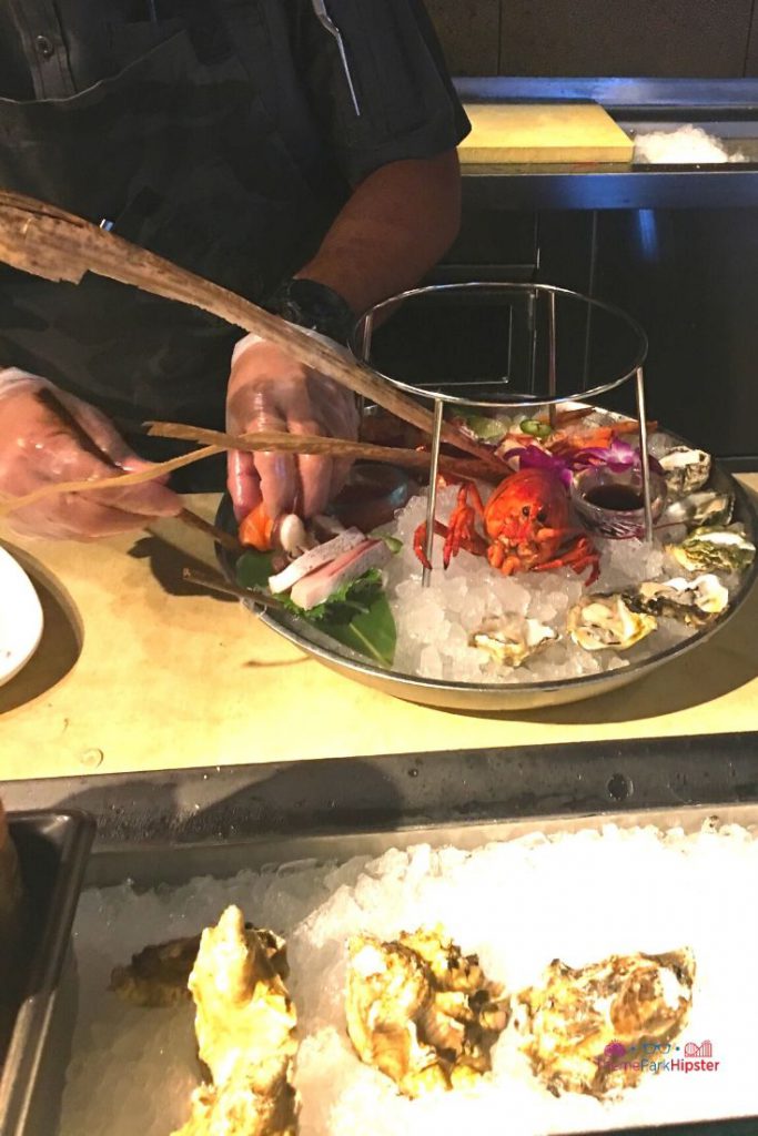 Morimoto Chef creating oyster plate with red lobster in the center in Disney Springs 