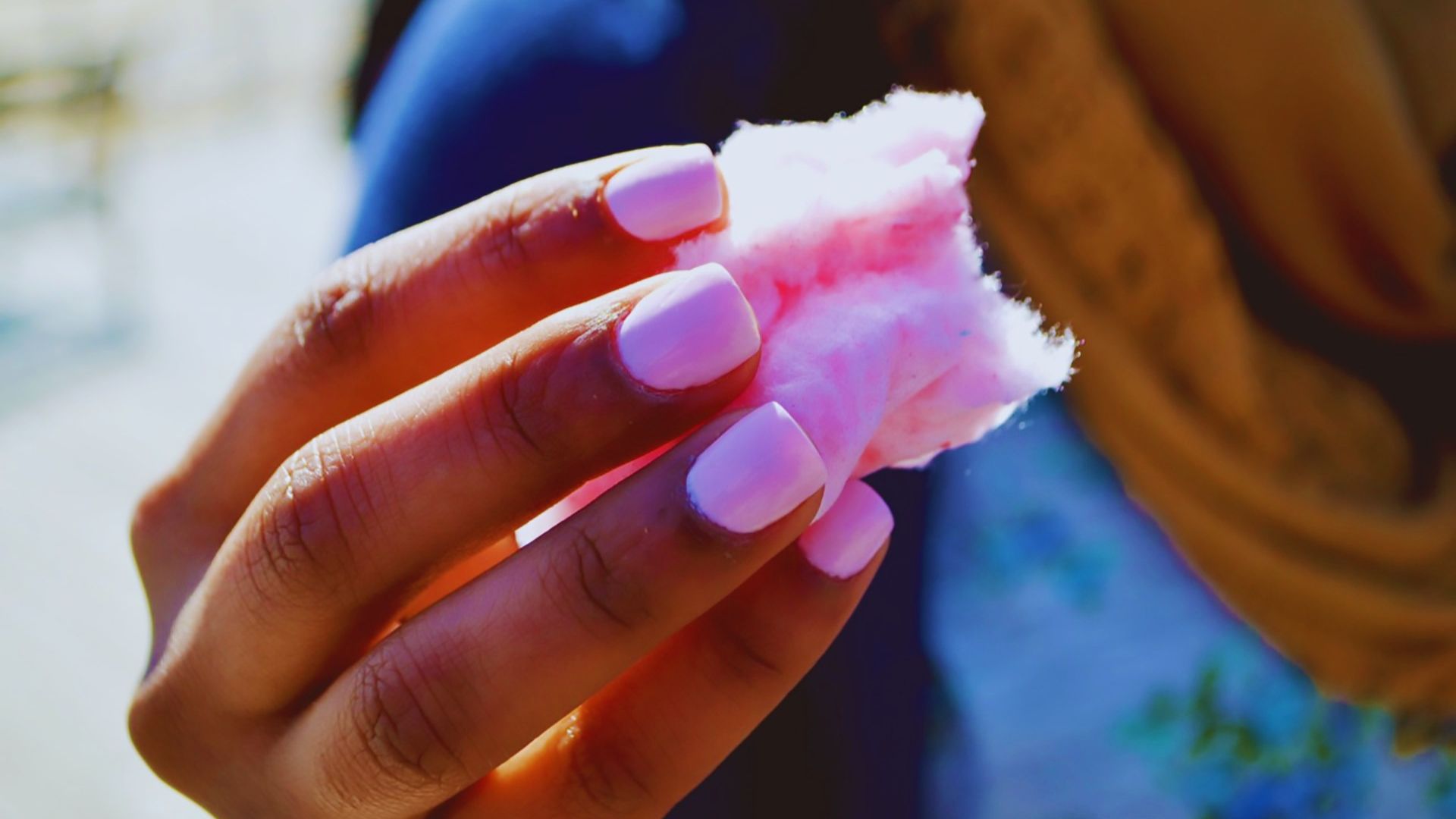 Lady holding pink cotton candy with pink nails at Disney World. Keep reading to learn about free things to do at Disney World and Disney freebies.