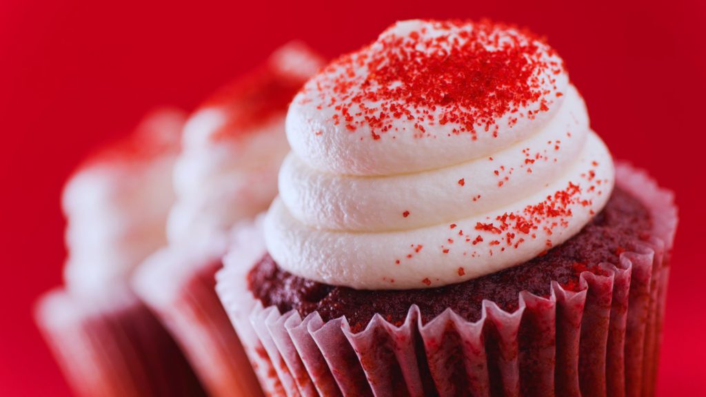Red velvet cupcake with red sprinkle on red background at Sprinkles in Disney Springs. Keep reading to learn about free things to do at Disney World and Disney freebies.