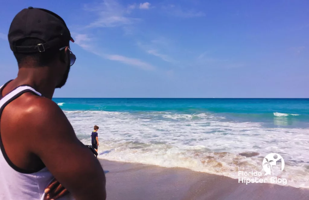 Man looking at the ocean in Jupiter Beach, Florida. Keep reading to get the best ways to beat the summer Florida heat. 
