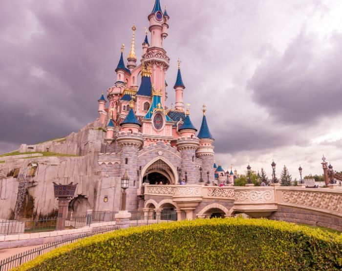 Solo Travel Tips for Theme Parks with Pink Sleeping Beauty Castle Disneyland Paris. Keep reading for the full female guide to solo travel.