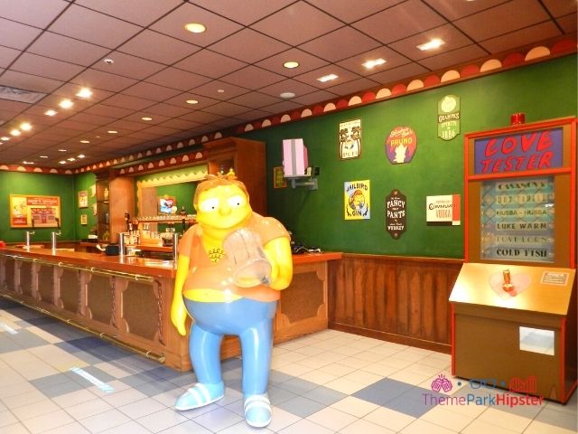 Moes Tavern Interior with Barnie Gumble and Love Tester Machine. Keep reading to get the best photos at Moe's Tavern Universal Studios and the menu.