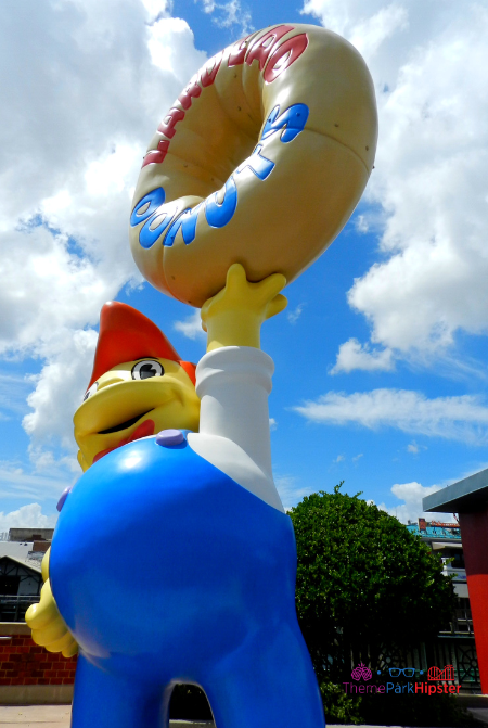 Lard Lad Big Yellow Donut with boy in blue overalls statue. Big Pink Simpsons donut at Universal Studios.