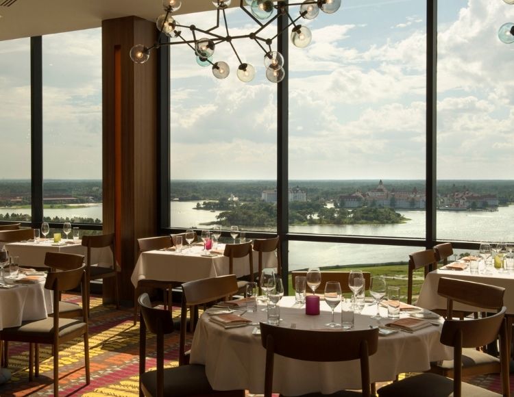 Disney view from California Grill, with fine dining seating in front of wall to ceiling windows. Keep reading to discover the most romantic things to do at Disney World for couples. 
