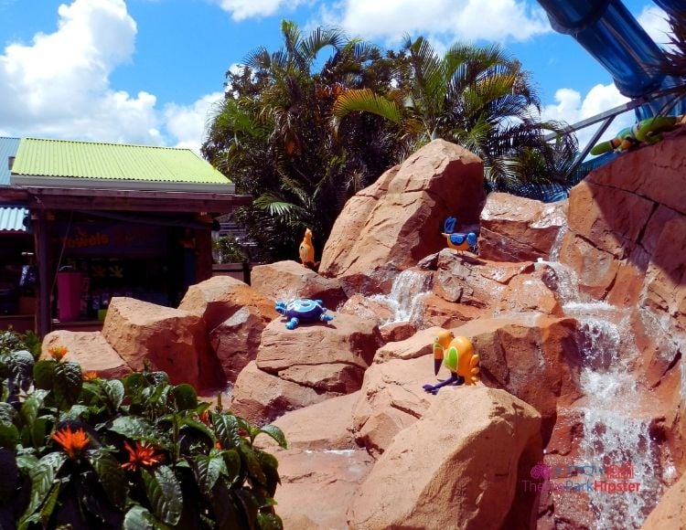 SeaWorld Aquatica Orlando Scenery with big rocks with running water over it with figurines of tropical wildlife. Keep reading for the complete Aquatica Orlando guide for beginners.