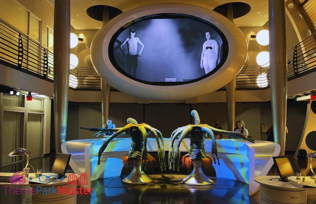 Men in Black Alien Attack Immigration Tour Universal with aliens in a futuristic control room scene. Keep reading to find out the best things to do on your Universal Studios solo trip.