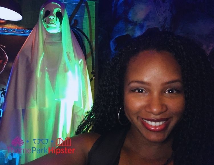 NikkyJ at Halloween Horror Nights 2017  with Ghost Lady nun with black eyes behind her. Keep reading to find out more about Halloween at Universal. 
