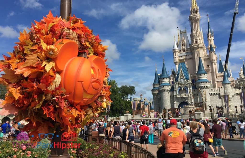 Mickey Mouse Halloween Pumpkin Head in front of Cinderella Castle at Magic Kingdom. Keep reading for more Halloween at Disney things to do and events with fall decor.