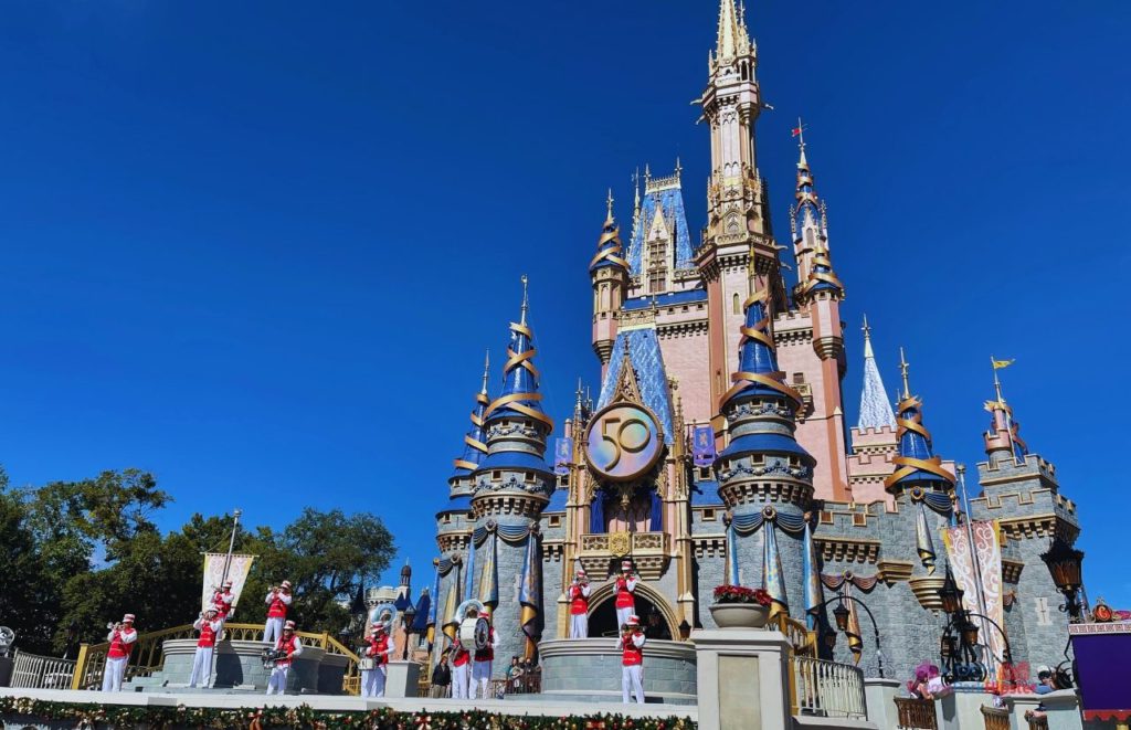 Cinderella Castle for 50th Anniversary Celebration with the Magic Kingdom Band Performing on the Stage. Keep reading to get the best things to do at the Magic Kingdom for Christmas and a full guide to Mickey's Very Merry Christmas Party Tips!