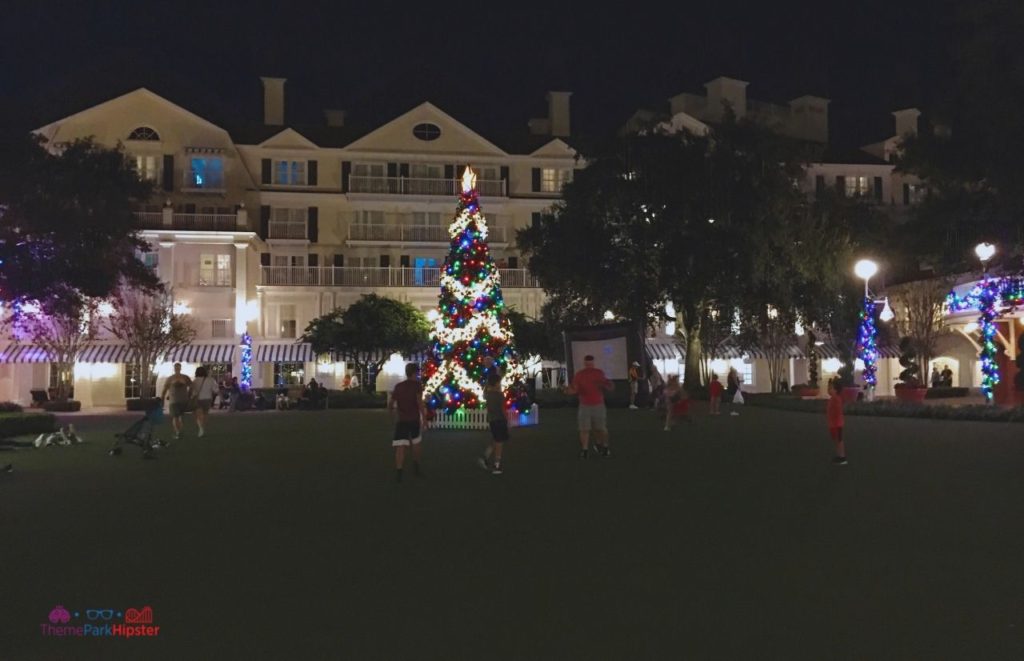 Disney Yacht Club Christmas Tree Outside People Watching Movie on the Lawn. Keep reading to learn about the best Disney Christmas trees!