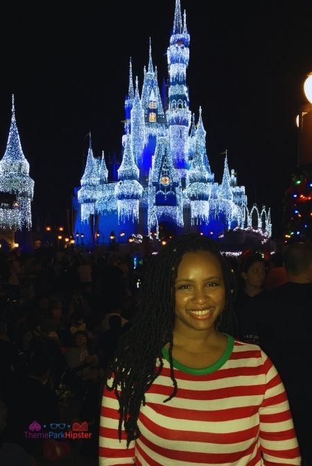 NikkyJ in front of sparkling Cinderella Castle at Christmas. Keep reading to get the best Disney Christmas quotes for the holidays!