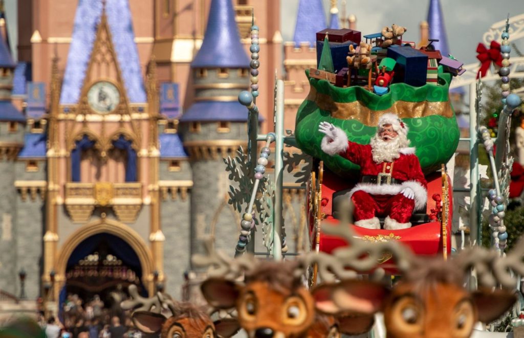 Santa on a sleigh with a big green bag of presents and reindeer in front of Santa at the Disney Christmas Parade, Magic Kingdom. Keep reading to discover more of the best things to do at Disney World for solo travelers.