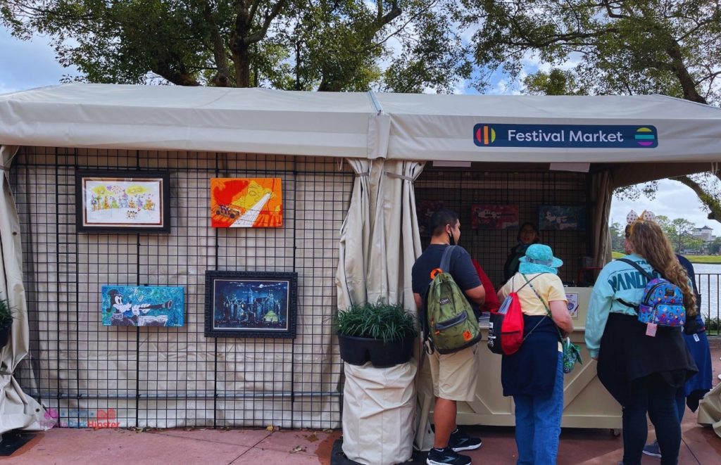 Epcot International Festival of the Arts 2023 Festival Market with Paintings. Keep reading to get the fun and best things to do at Epcot Festival of the Arts!