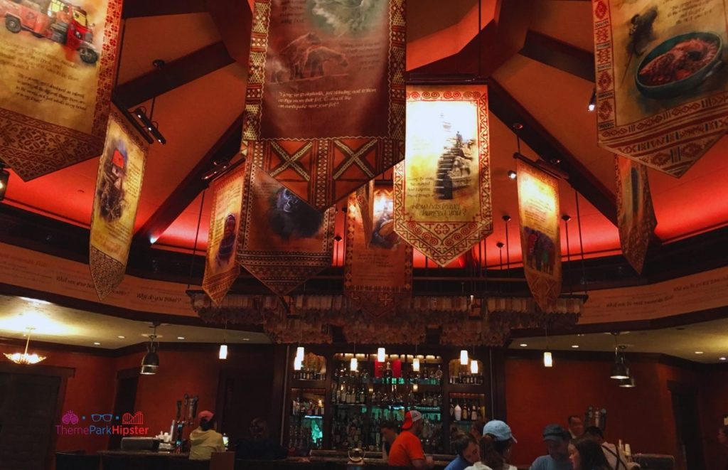 Interior design of Nomad Lounge in Animal Kingdom with hanging banners and bar. Keep reading to find out the best things to do at Disney World for adults.