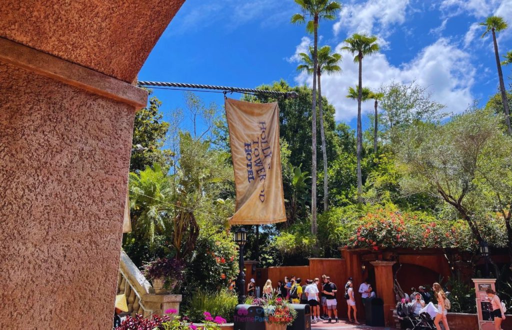 Brown flag the reads "Hollywood Tower Hotel" hanging from the tan stucco exterior of The Twilight Zone Tower of Terror at Disney World Hollywood Studios. If you want to take deep dive into Twilight Zone Tower of Terror: Secrets REVEALED, keep reading!