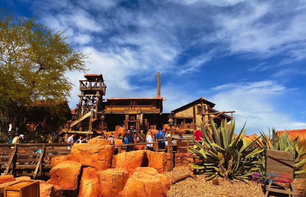 Big Thunder Mountain Railroad entrance in Frontierland at Disney Magic Kingdom, with American old west pioneer structures. Keep reading to find out more about the best place to watch Magic Kingdom fireworks. 