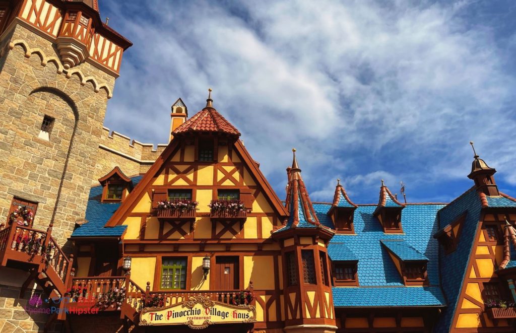 The Pinocchio Village Haus Restaurant designed with Swiss style architecture in blues yellow and brown in Fantasyland at Disney Magic Kingdom. Keep reading to find out more about the best place to watch Magic Kingdom fireworks. 