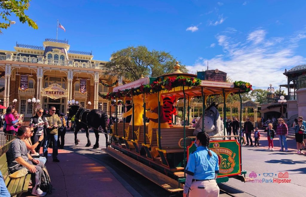 Disney Magic Kingdom Holiday Christmas Trolley with Winnie the Pooh Tigger in front of Theater. Keep reading to learn more about your Disney Christmas trip and the Disney Christmas decorations.