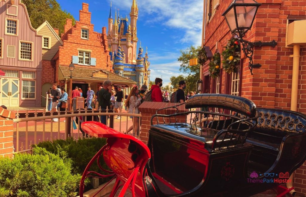 Disney Magic Kingdom Ye Olde Christmas Shoppe in Liberty Outside with Santa sleigh in front of Cinderella Castle. Keep reading to know what to pack and what to wear to Disney 
World in December for your packing list.