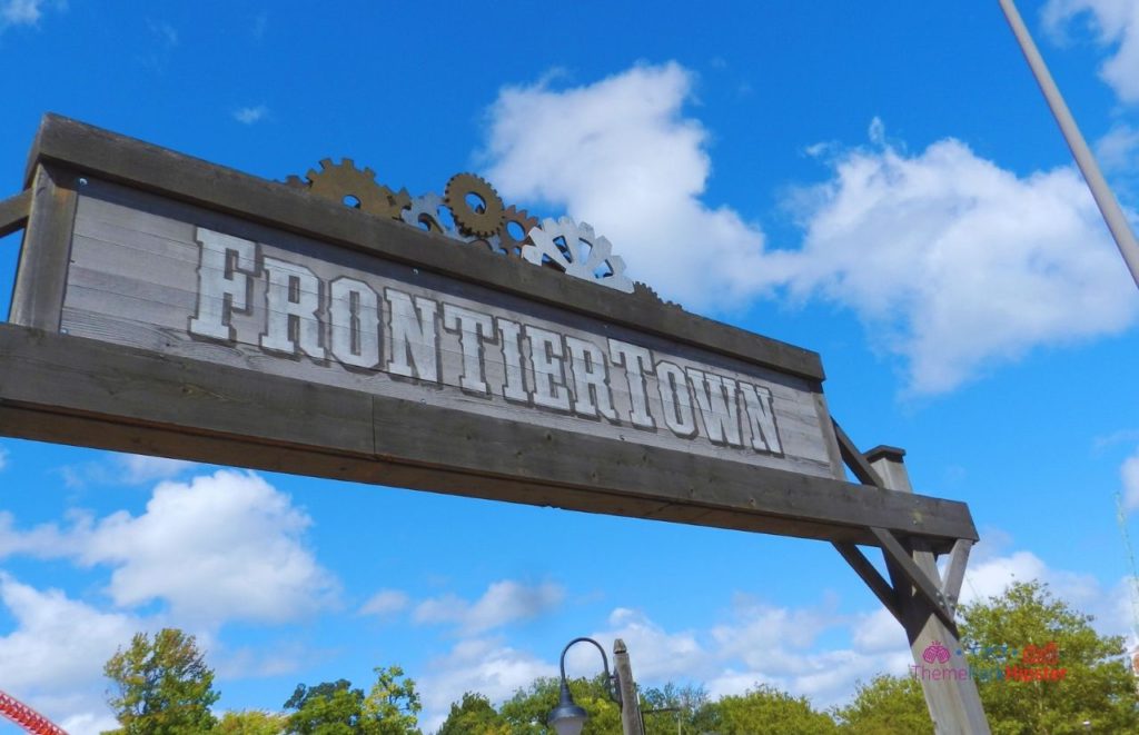 Cedar Point's FrontierTown entrance sign, with the name "FrontierTown" written in old timey Western front and rusted gears on top the wooden sign. Keep reading if you want to learn more about the history, theme, ride stats and fun facts about the Maverick at Cedar Point!