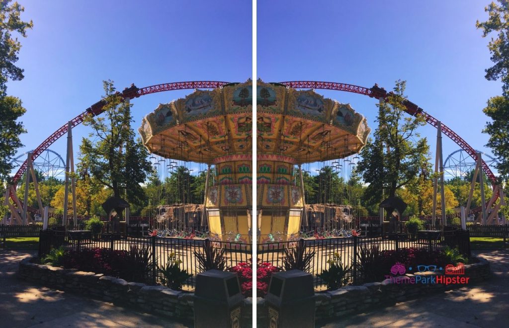 The large yellow swing ride known as the Wave Swinger sits in natural position as the Maverick Roller Coaster soars through the sky in the distance. Keep reading if you want to learn more about the history, theme, ride stats and fun facts about the Maverick at Cedar Point!