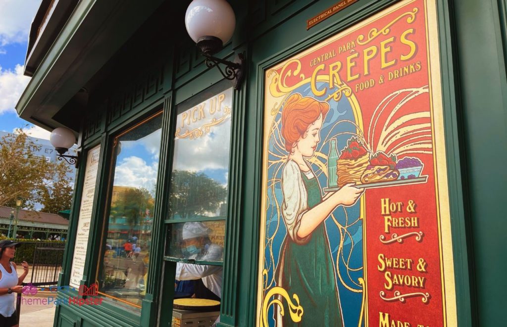 Walk up window and colorful vintage sign of Universal Orlando Resort Central Park Crepes at Universal Studios Florida. Keep reading to learn all the best things to do on a Universal Studios solo trip.  