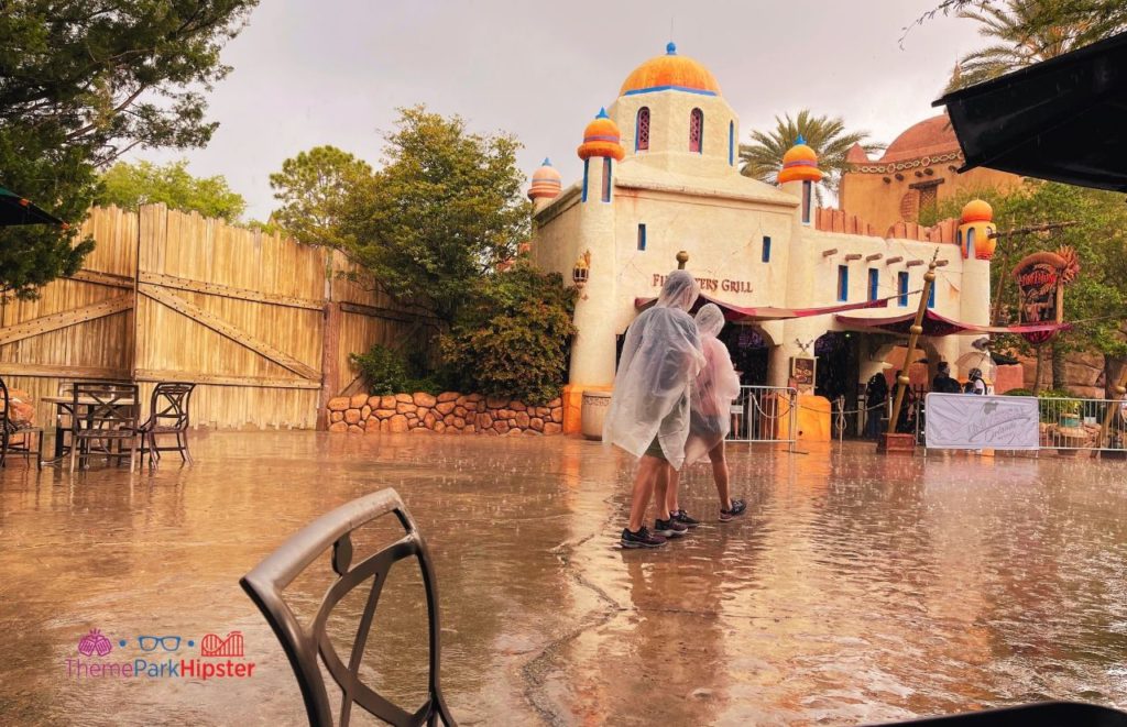 Universal Orlando Resort Fire Eater Grill Rainy Day at Islands of Adventure with theme park guests in ponchos. Keep reading to learn more about what to pack for Universal Studios Florida.