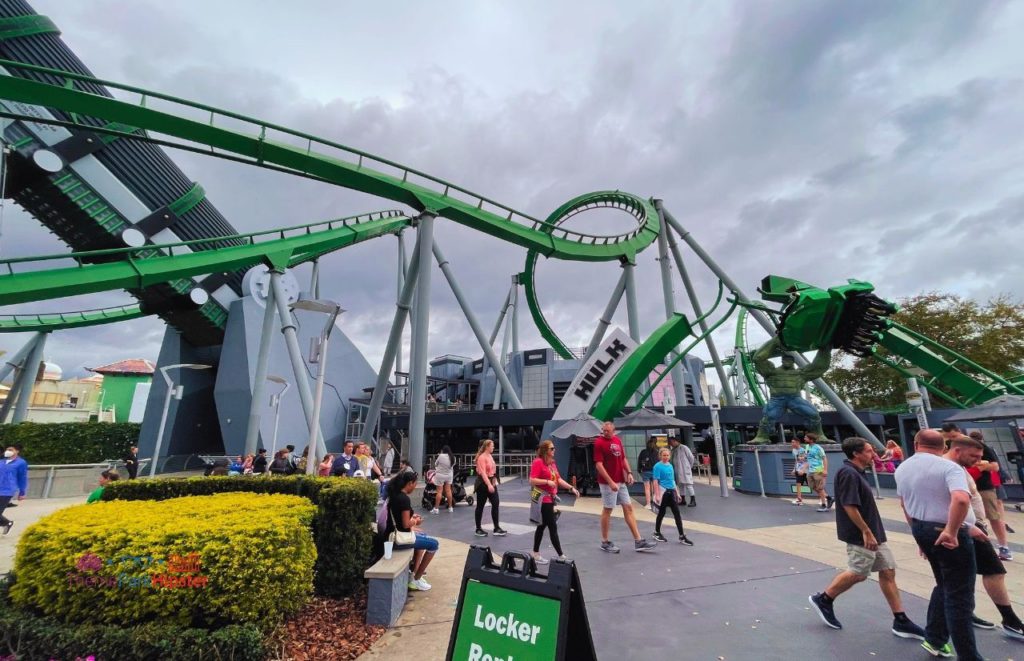 Universal Orlando Resort Hulk Roller Coaster at Islands of Adventure with theme park visitors walking underneath. Keep reading to find out more about Hulk vs VelociCoaster at Universal Orlando.