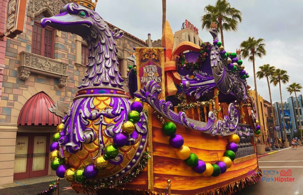 Massive purple Krewe of Dionysus Swan Float for Mardi Gras celebration riding down to street of Universal Studios Florida. Keep reading to to find out more Mistakes to Avoid at Universal Orlando Resort!