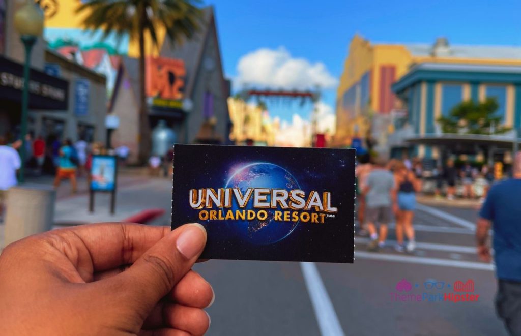 Hand holding a Universal Orlando Resort ticket at Universal Studios Florida. Keep reading to to find out more Mistakes to Avoid at Universal Orlando Resort!