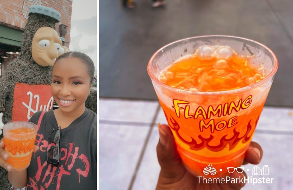 NikkyJ a black woman traveler holding a Flaming Moe orange drink at Universal Orlando Resort in Simpsons Land at Universal Studios Florida. Keep reading to find out what are the best Universal Orlando Snacks under $10.