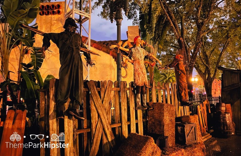 Scarecrows propped up and hanging in above the fence in the Scarecrow Scare Zone HHN 31 during Halloween Horror Nights 2022 at Universal Orlando. Keep reading to find out more about Halloween Horror Nights Stay and Scream.