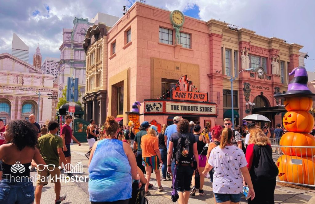 Halloween Horror Nights 2024 Universal Orlando with guests walking around in comfortable clothing outside the Tribute Store with Halloween decorations on display. Keep reading to find out what to wear to Halloween Horror Nights.