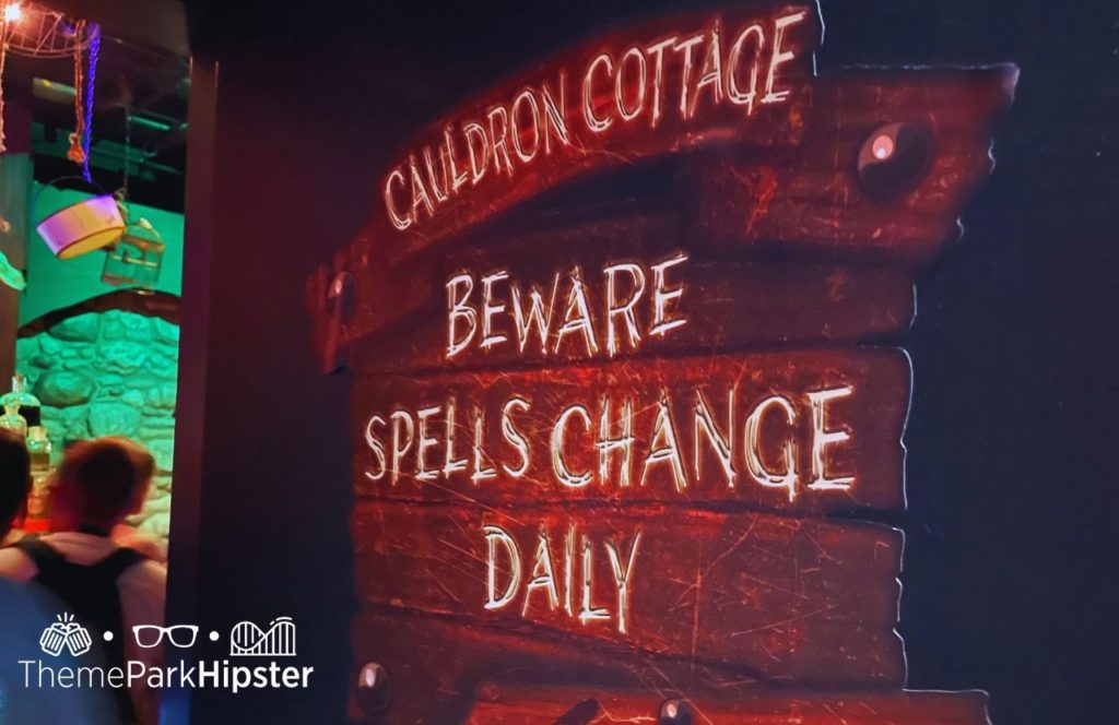 Cauldron Cottage sign stating Beware Spells Change Daily in Witch’s Cottage Tribute Store Merchandise HHN 31 at Halloween Horror Nights 2022 Universal Orlando. Keep reading to see if the Halloween Horror Nights Express Pass is worth it.  