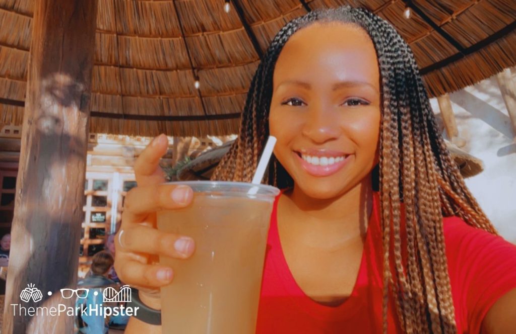 Nikky J at Islands of Adventure, Universal Orlando Resort, with a Long Island iced tea under a thatched umbrella. Keep reading to learn more about the best bars at Universal Orlando.